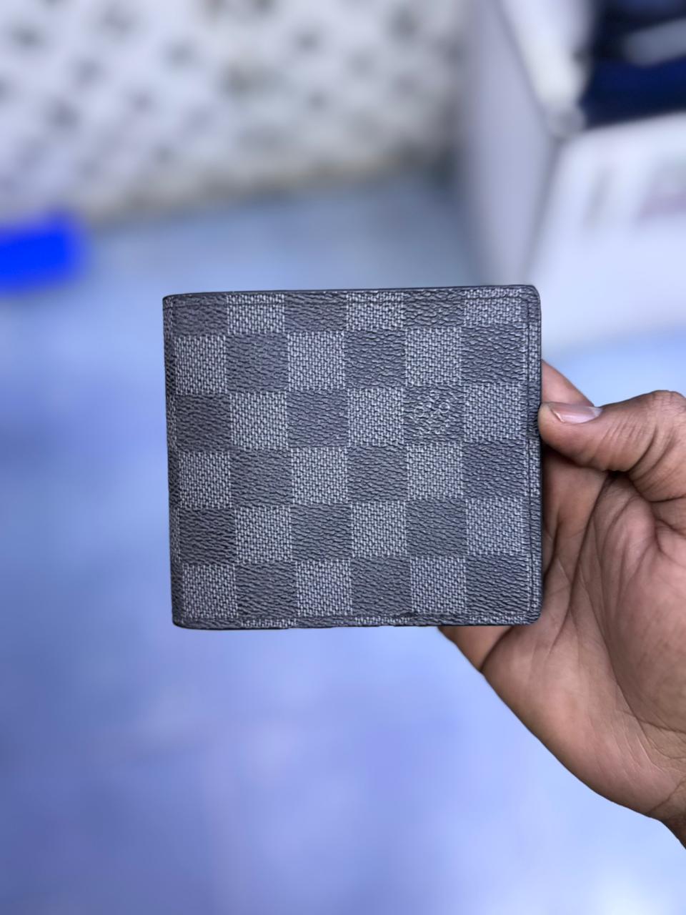 Hand holding a checkered wallet against a blurred background