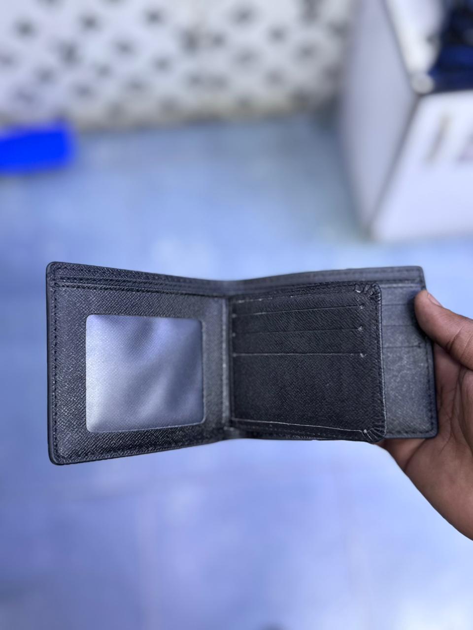 Black wallet held by a hand on a blurred background