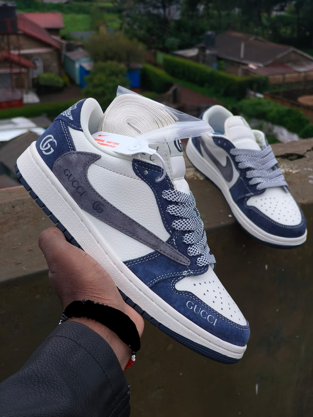 Pair of Gucci sneakers held by a hand with a blurred background