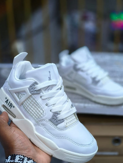 White sneaker held in a hand with a blurred background