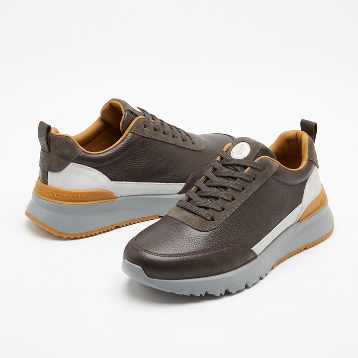 Brown lace-up sneakers with light grey soles and mustard heel accents on white
