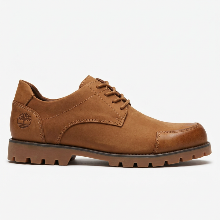 Tan lace-up Derby-style shoe with stitched toe panel and brown lug sole on white background